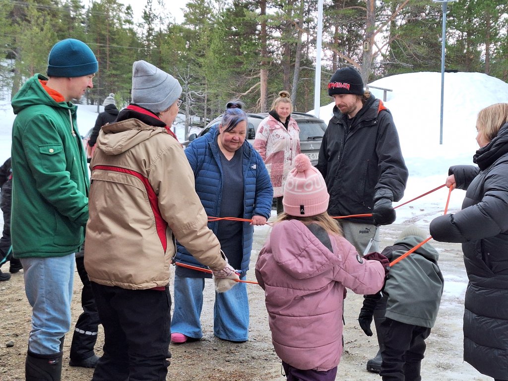 Leiriläiset ulkona leikkimässä perinteistä kolttasaamelaista naruleikkiä
